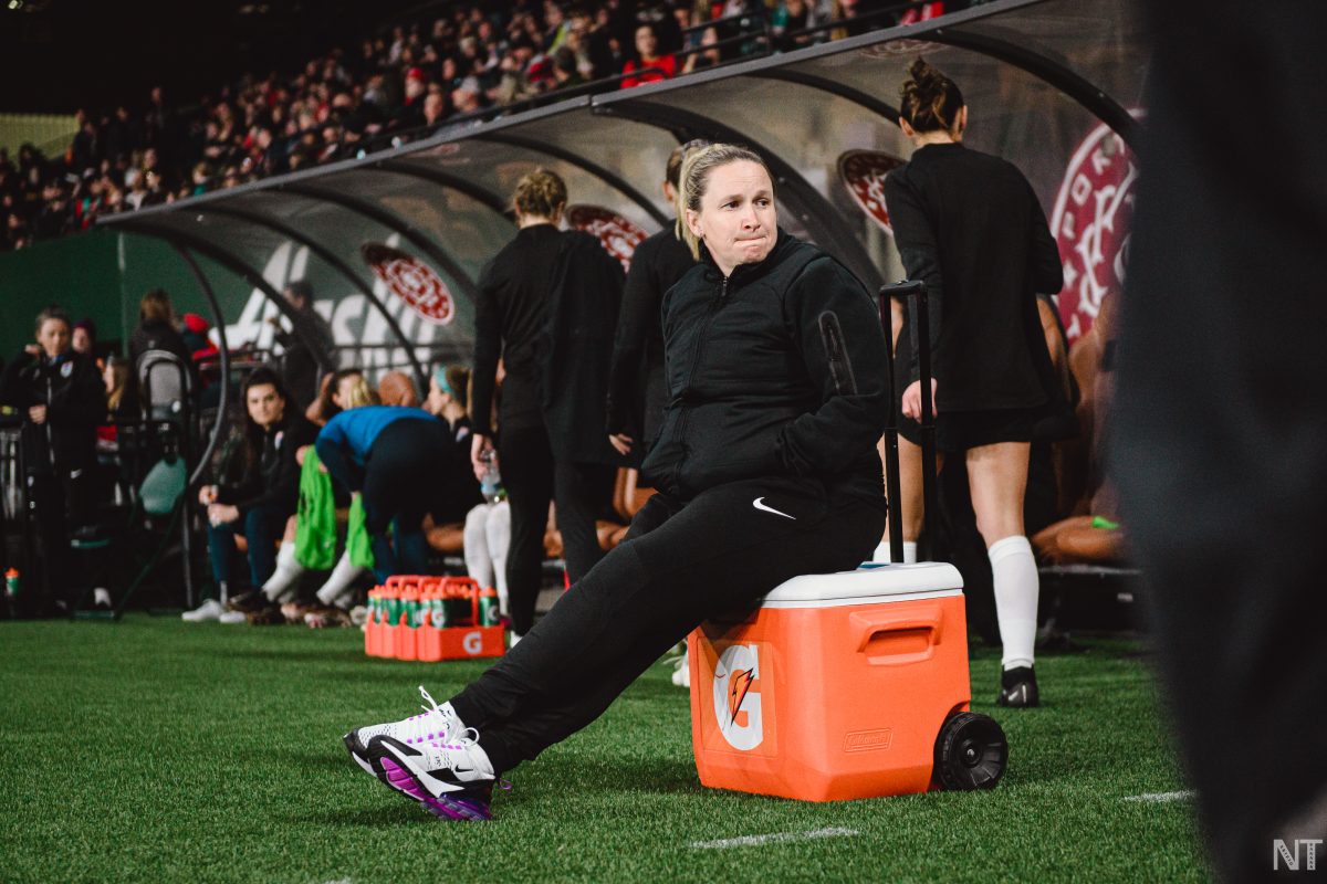 Portland Thorns Head Coach Laura Harvey sitting on a cooler. (Photo by Nikita Taparia)